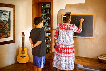 Woman writing equation on blackboard for son