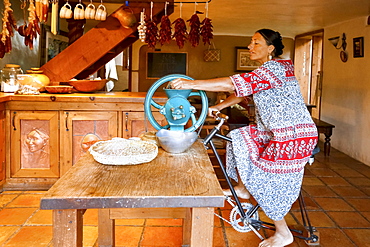 Woman pedaling to power grinder in kitchen