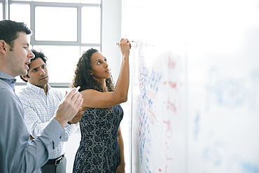 Businesswoman writing on whiteboard in meeting