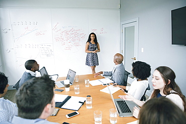 Businesswoman talking at whiteboard in meeting