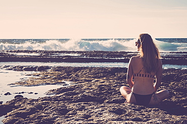 Caucasian woman sitting on beach wearing bikini