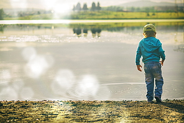 Boy watching ripples in lake