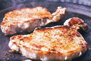 Pork chops searing in pan