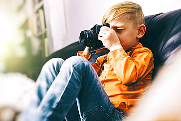 Caucasian boy sitting on sofa using camera