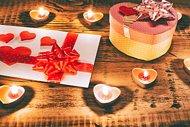 Valentine candles burning on table with gift box and card