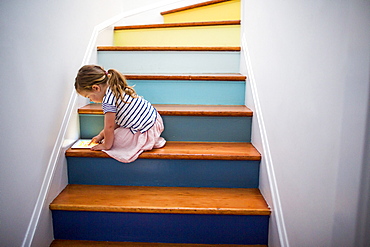 Caucasian girl using digital tablet on multicolor staircase