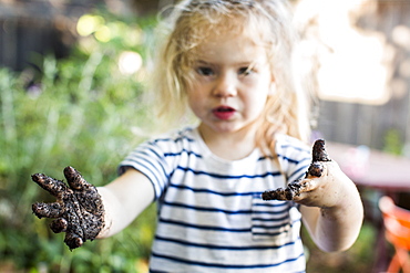 Caucasian girl with muddy hands in garden