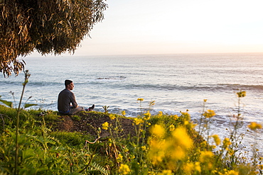 Caucasian man admiring scenic view of ocean at sunset