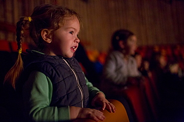 Girl leaning on chair watching movie in theater