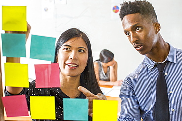 Woman and man reading adhesive notes in office