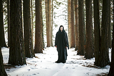 Caucasian man with beard wearing robe in forest during winter