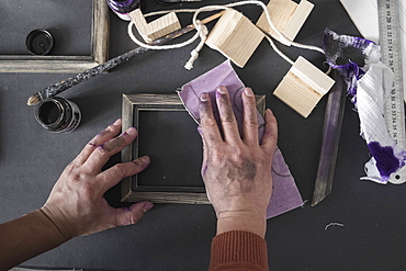 Hands of Caucasian artist sanding picture frame