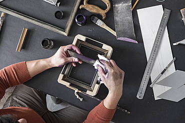 Hands of Caucasian artist staining picture frame