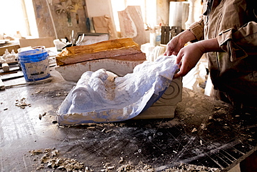 Caucasian artist lifting mold from plaster