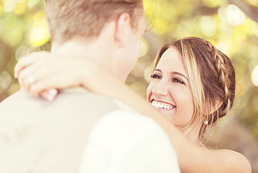 Caucasian bride and groom hugging outdoors