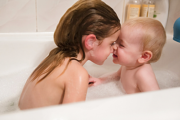 Caucasian brother and sister rubbing noses in bubble bath