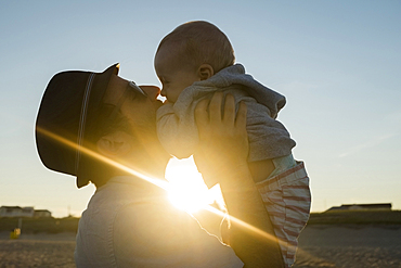 Sun beaming between Caucasian father and baby son