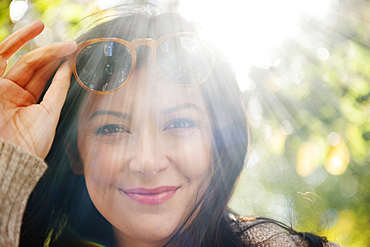 Sunbeams on Caucasian woman raising sunglasses