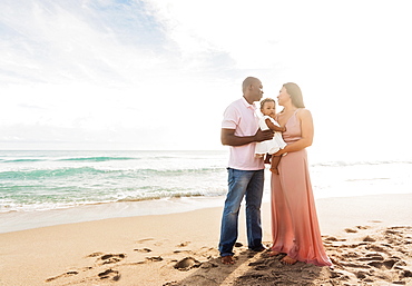 Couple holding baby daughter on beach