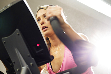 Mixed Race woman riding stationary bicycle