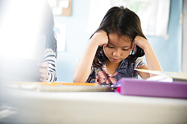 Frustrated girl with head in hands in classroom