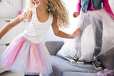 Girls wearing tutus dancing on sofa