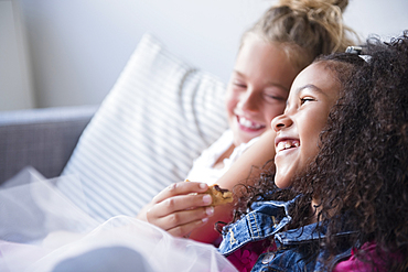 Smiling girls eating cookie on sofa