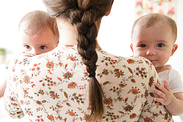 Caucasian mother holding twin baby daughters