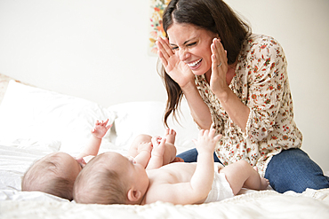 Caucasian mother playing hide-and-seek with twin baby daughters