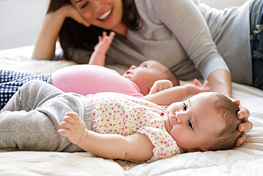 Caucasian mother caressing head of baby daughter on bed