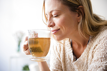 Caucasian woman smelling cup of tea