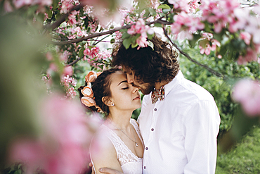 Middle Eastern couple kissing under flowering tree