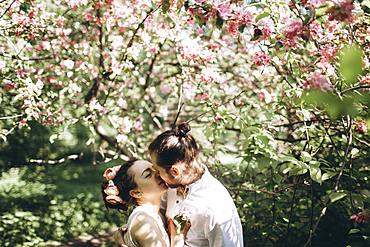 Middle Eastern couple kissing under flowering tree