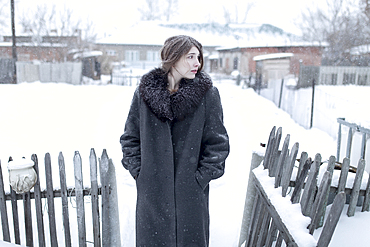 Caucasian woman wearing coat in winter near fence