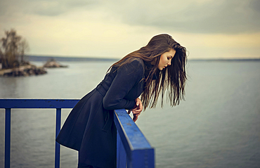 Caucasian woman leaning on railing at waterfront