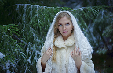 Caucasian woman wearing fur coat in snowy forest