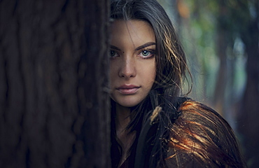 Caucasian woman leaning on tree trunk