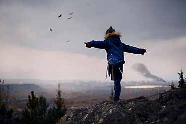 Caucasian girl balancing on rocks imitating flying birds