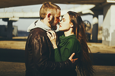 Caucasian couple hugging woman outdoors