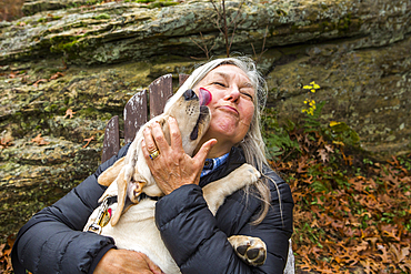 Dog licking face of Caucasian woman outdoors