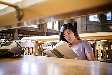 Chinese woman sitting in library reading book