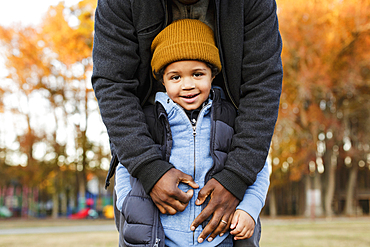 Father leaning over son in park