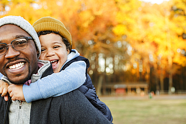 Father carrying son piggyback in park