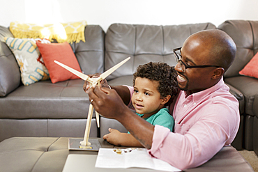 Father and son building model windmill in livingroom