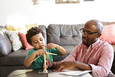 Father and son building model windmill in livingroom