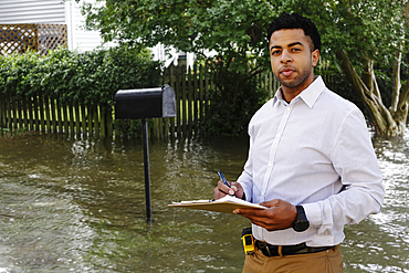 Black insurance adjuster examining flooding damage to house