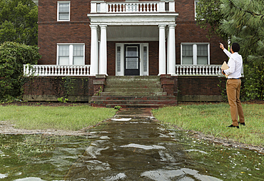 Black insurance adjuster examining flooding damage to house