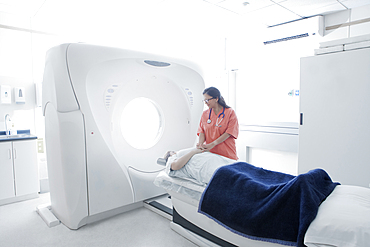 Hispanic nurse comforting patient at scanner