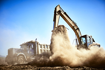 Truck near digger in dirt field