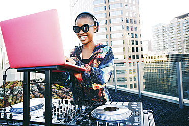 Smiling Black DJ on urban rooftop